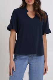 Model Madeline wearing size 10 of the Ruffle Tee Top in colour Navy (Blue), from the front, cropped image
