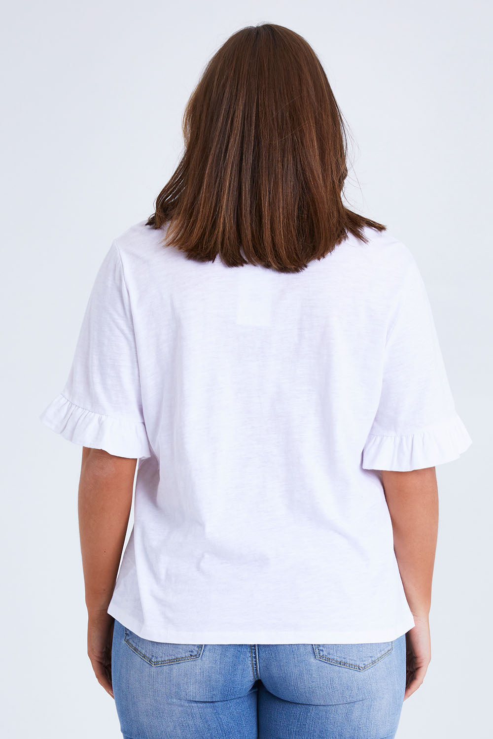 Model Monique wearing size 14 of the Ruffle Tee Top in colour White (White), from the back