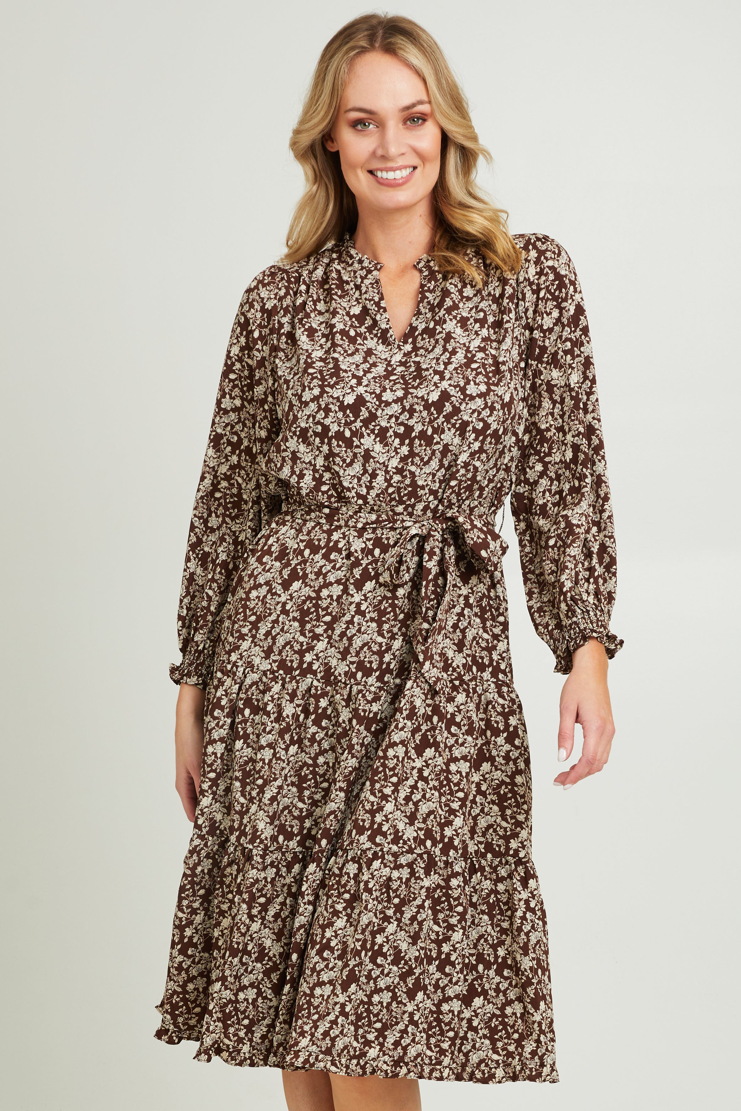 Model Grace wearing size 10 of the Felicia Dress in colour Mocha, from the front, cropped image