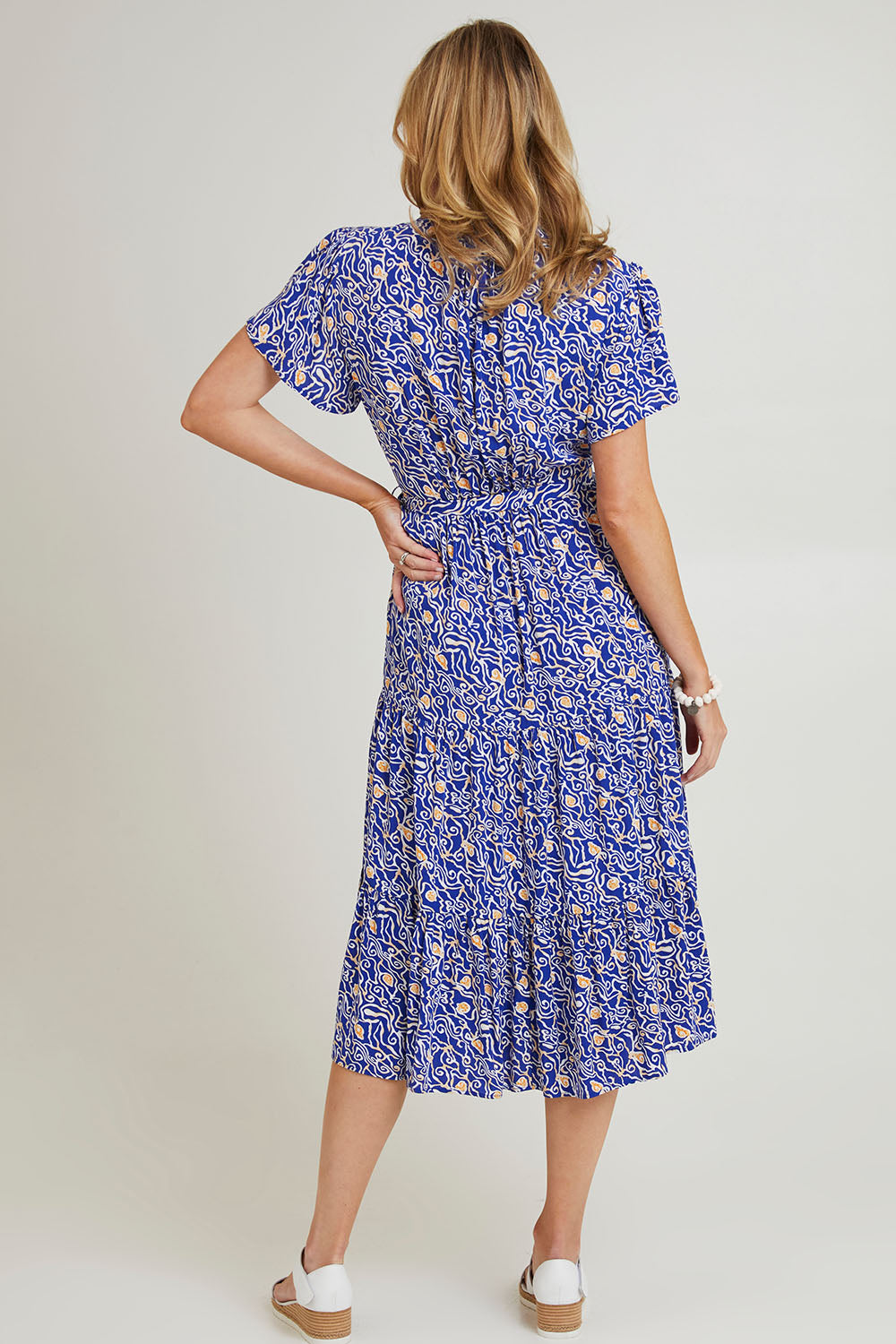 Model Grace wearing size 10 of the Wrap Flutter Dress in colour Royal (Blue), from the back