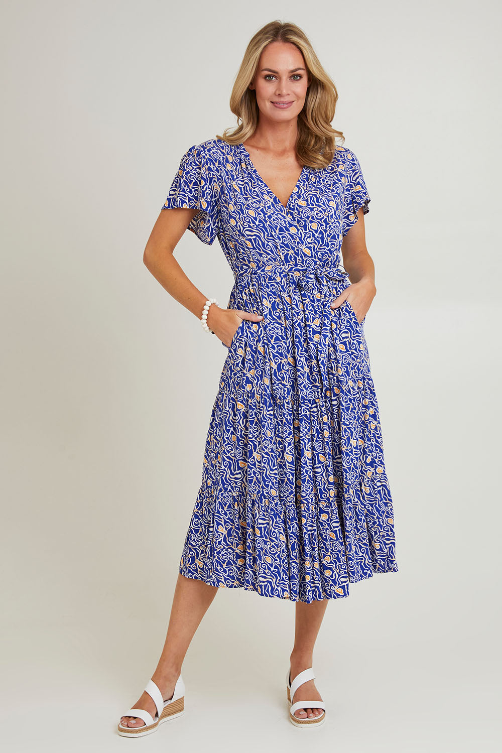 Model Grace wearing size 10 of the Wrap Flutter Dress in colour Royal (Blue), from the front, showing the whole outfit