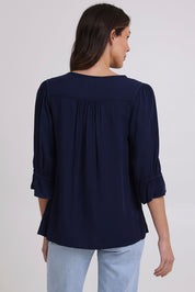 Model Madeline wearing size 10 of the Floriana Core Top in colour Navy (Blue), from the back