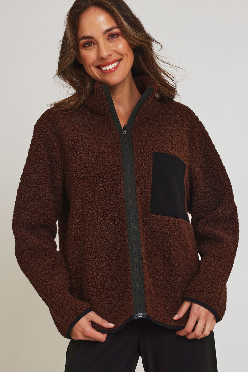 Model Madeline wearing size 10 of the Teddy Zippy Jacket in colour Choc, from the front, cropped image