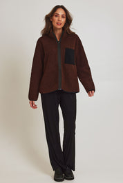 Model Madeline wearing size 10 of the Teddy Zippy Jacket in colour Choc, from the front, showing the whole outfit