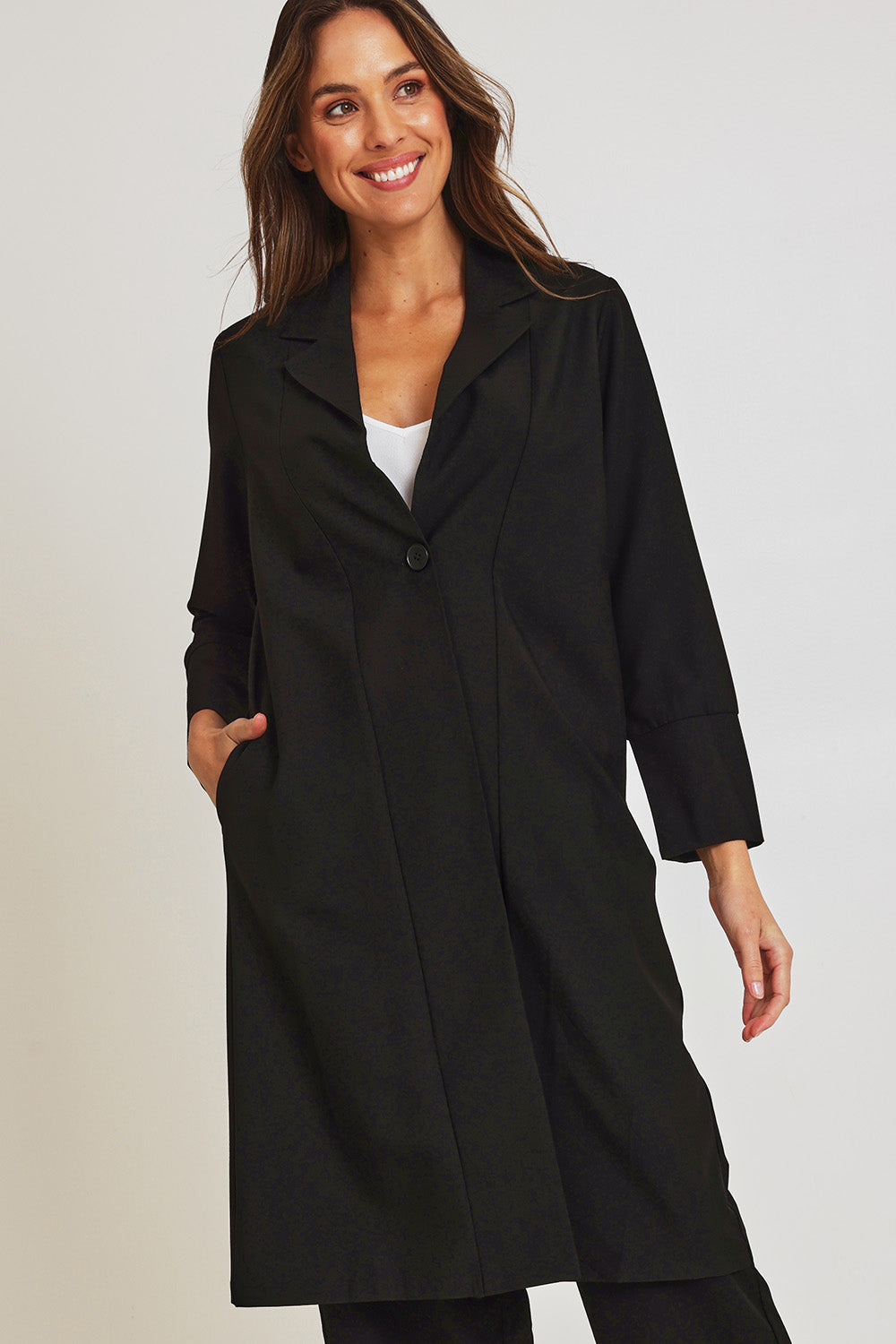 Model Madeline wearing size 10 of the Fluid Longline Jacket in colour Black (Black), from the front, cropped image