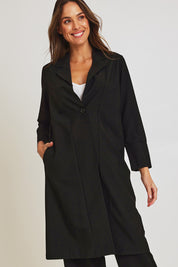 Model Madeline wearing size 10 of the Fluid Longline Jacket in colour Black (Black), from the front, cropped image