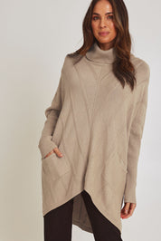 Model Madeline wearing the Polo Tunic Knit Jumper in colour Sand, from the front, cropped image