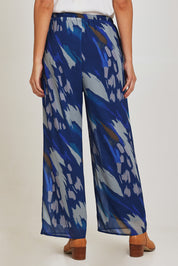 Model Madeline wearing size 10 of the Abstract Pant in colour Blueprint (Blue), from the back