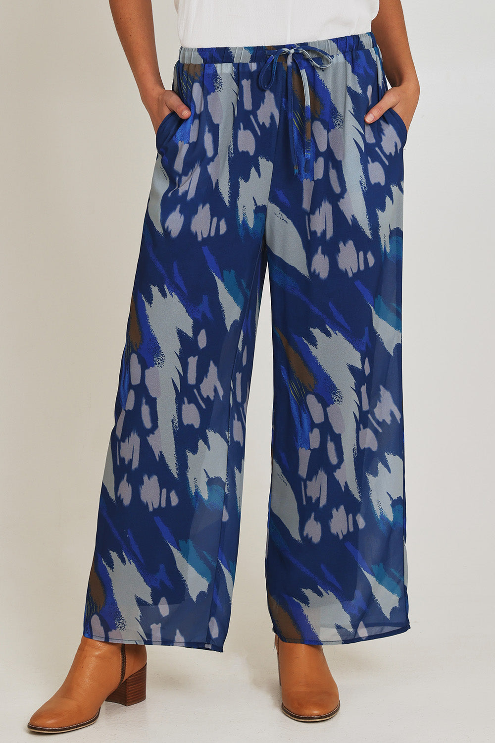 Model Madeline wearing size 10 of the Abstract Pant in colour Blueprint (Blue), from the front, cropped image