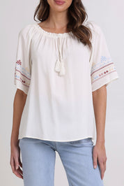 Model Madeline wearing size 10 of the Oakley Embroidered Top in colour Ivory (White), from the front, cropped image