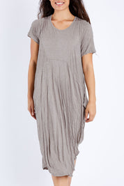 Model Larissa wearing size S-M of the In Bloom Flowing Dress in colour Oatmeal, from the front, showing the whole outfit