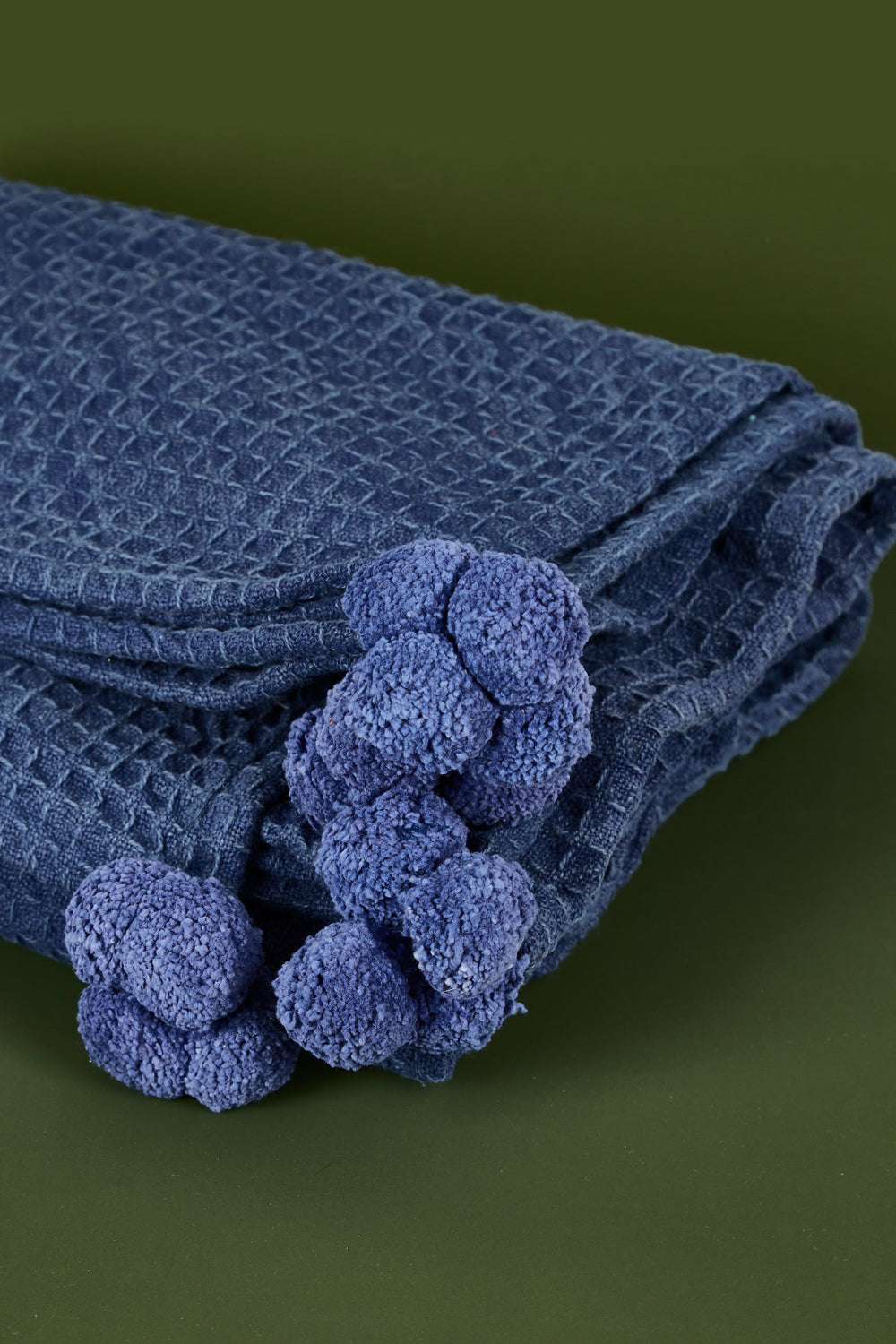 A model wearing size OneSize of the Textured Cotton Throw With Pompoms in colour Navy (Blue), from the front, showing the whole outfit