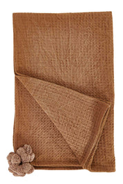 Product shot of the Textured Cotton Throw With Pompoms in colour Rust, from the front