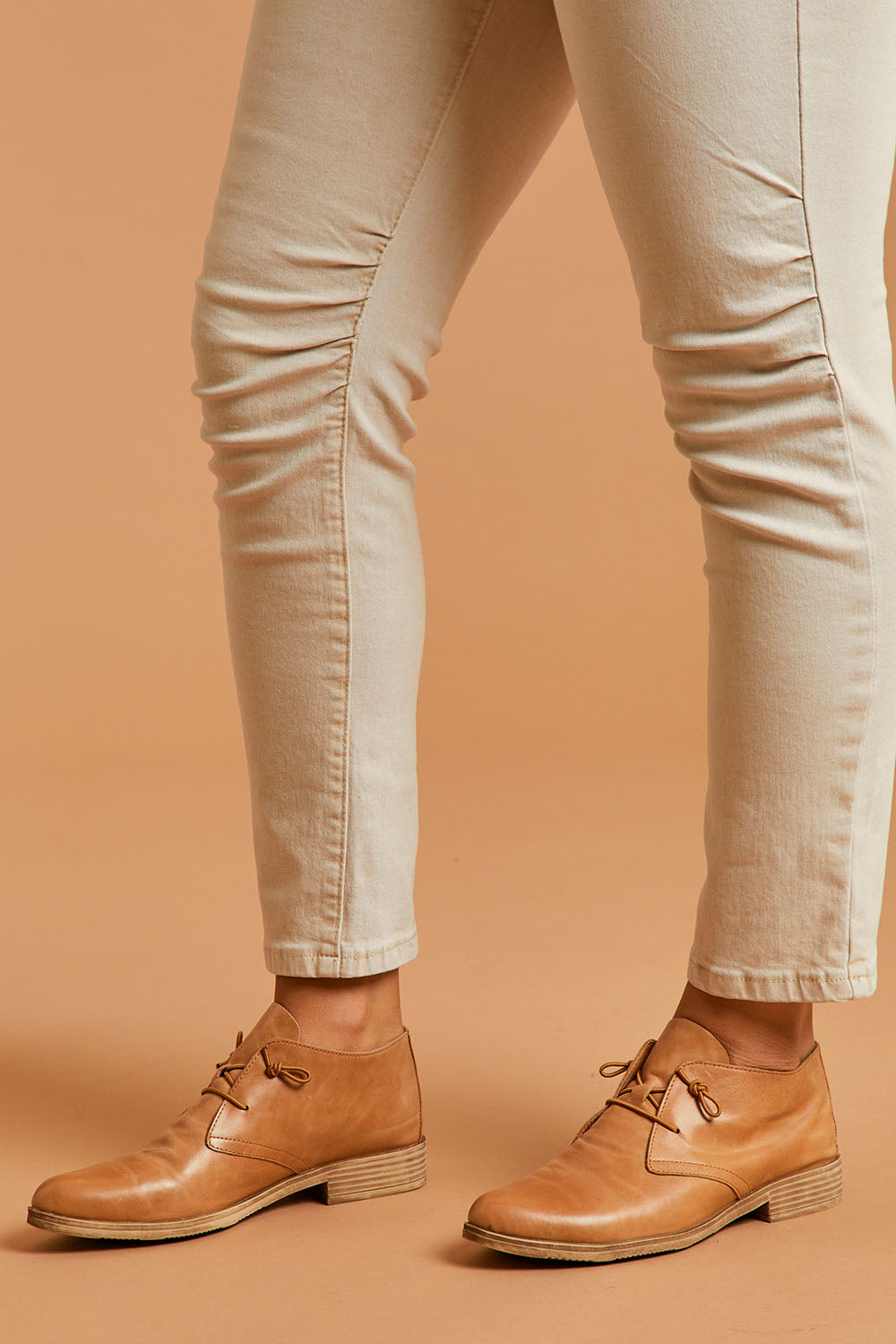 A model wearing size 39 of the Karaf Flat in colour Tan, from the front, cropped image