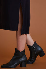 A model wearing size 40 of the Mockas Ankle Boot in colour BlackBlack (Black), from the front, cropped image