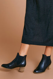 A model wearing size 38 of the Sadore Boot in colour Black (Black), from the front, cropped image