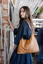 A model wearing the Adele Large Leather Bag in colour Tan, from the front, showing the whole outfit