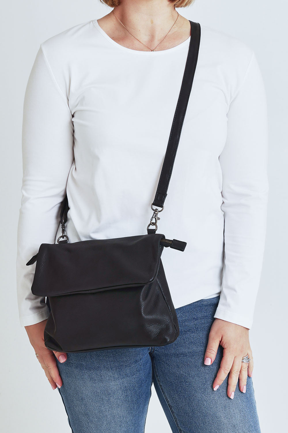 Model Steph wearing size OneSize of the Delphi Leather Bag in colour Black (Black), from the front, cropped image