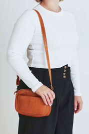 Model Steph wearing size OneSize of the Head In The Clouds Leather Bag in colour Tan, from the front, cropped image