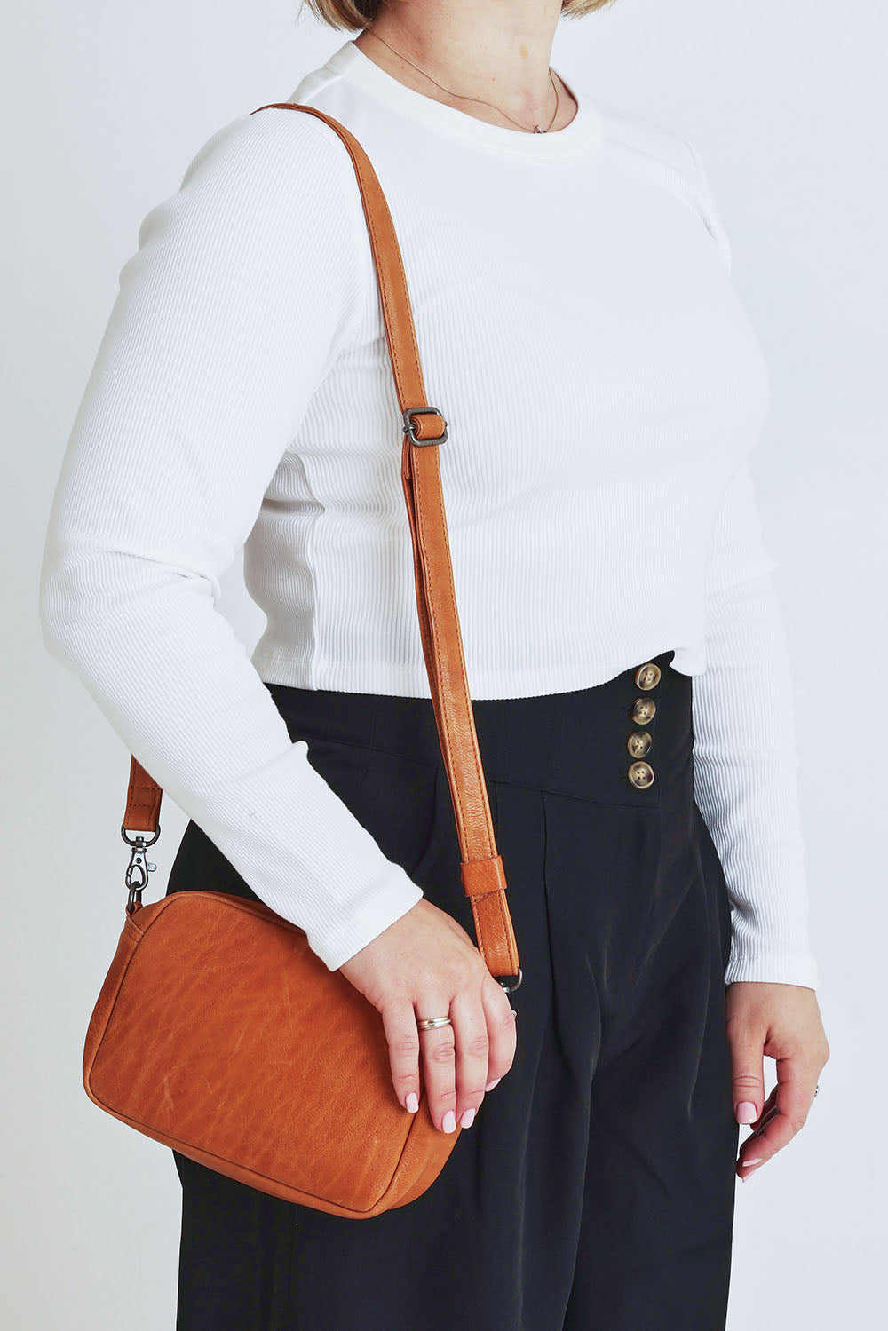 Model Steph wearing size OneSize of the Head In The Clouds Leather Bag in colour Tan, from the front, cropped image