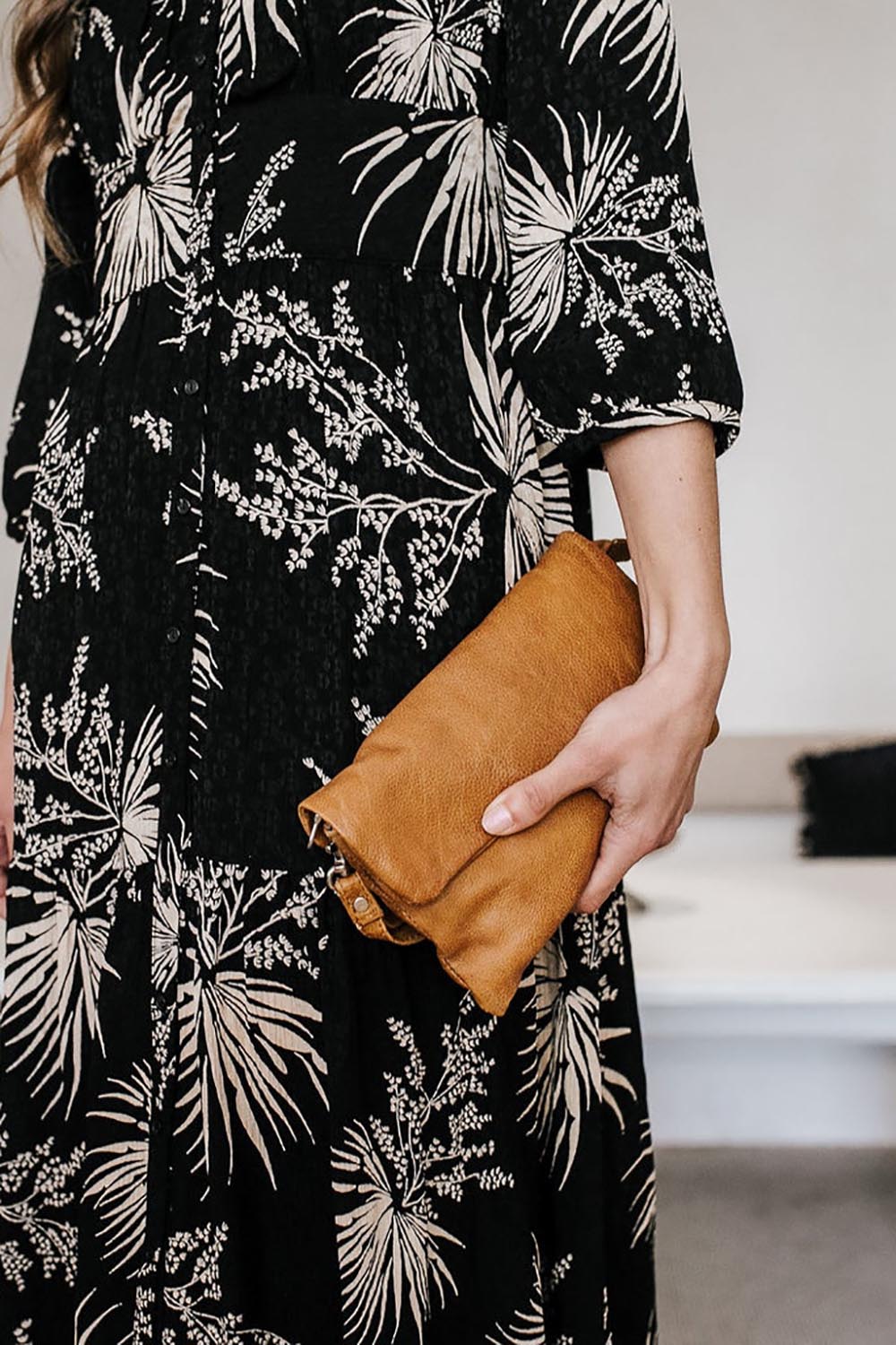 A model wearing the Lucie Leather Clutch Bag in colour Tan, from the front, showing the whole outfit