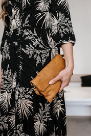 A model wearing the Lucie Leather Clutch Bag in colour Tan, from the front, showing the whole outfit