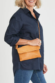 Model Sandy wearing size OneSize of the Lucie Leather Clutch Bag in colour Tan, from the front, cropped image