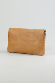 A model wearing the Mila Leather Foldover Purse in colour Sand, from the front, showing the whole outfit