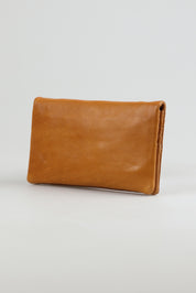 A model wearing the Mila Leather Foldover Purse in colour Tan, from the front, showing the whole outfit