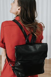 A model wearing the Neve Leather Backpack in colour Black (Black), from the front, showing the whole outfit