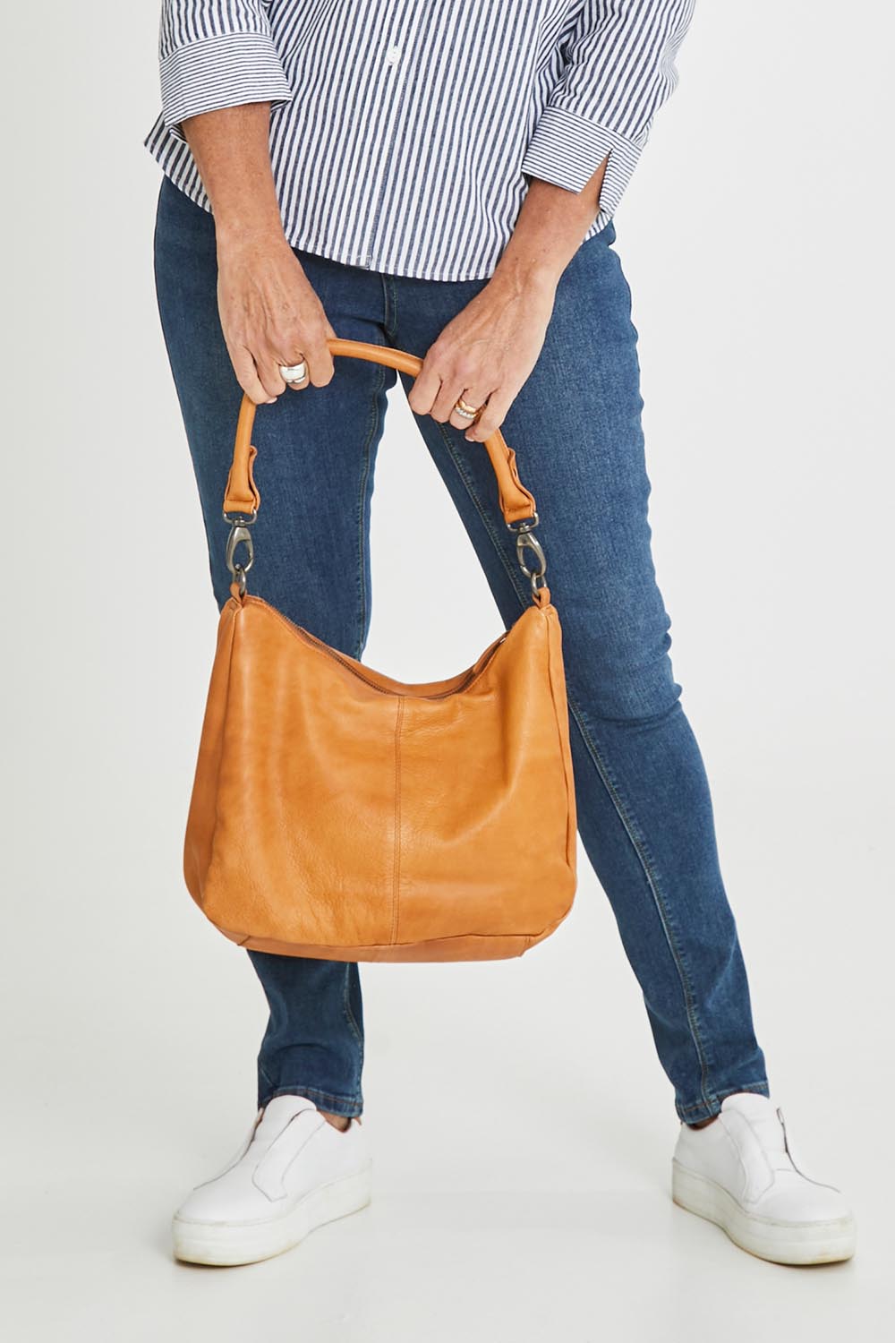 Model Sandy wearing size OneSize of the Poppy Leather Bag in colour Tan, from the front, cropped image