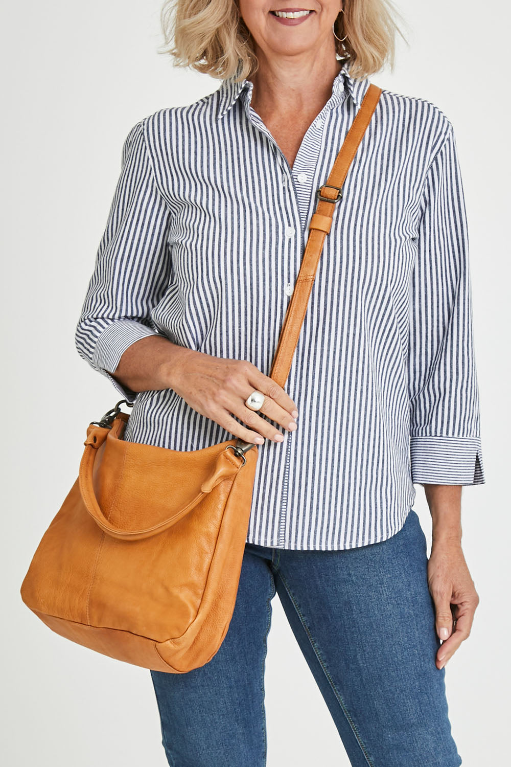 Model Sandy wearing size OneSize of the Poppy Leather Bag in colour Tan, from the front, cropped image