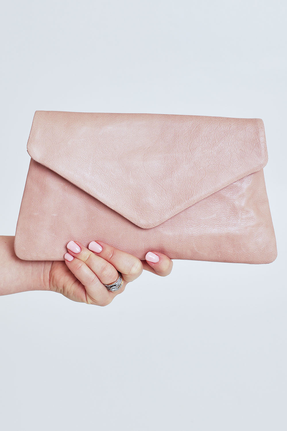 Model Steph wearing the Riley Leather Clutch in colour Duskypink (Pink), from the front, cropped image