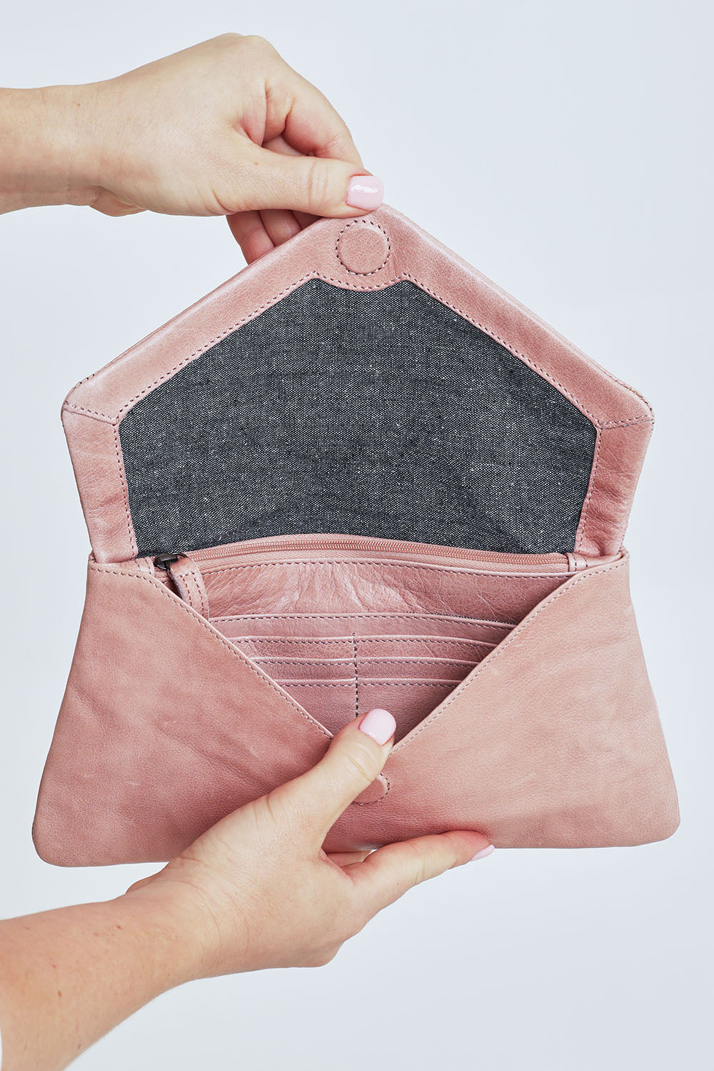 Model Steph wearing the Riley Leather Clutch in colour Duskypink (Pink), from the front, cropped image