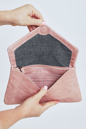 Model Steph wearing the Riley Leather Clutch in colour Duskypink (Pink), from the front, cropped image