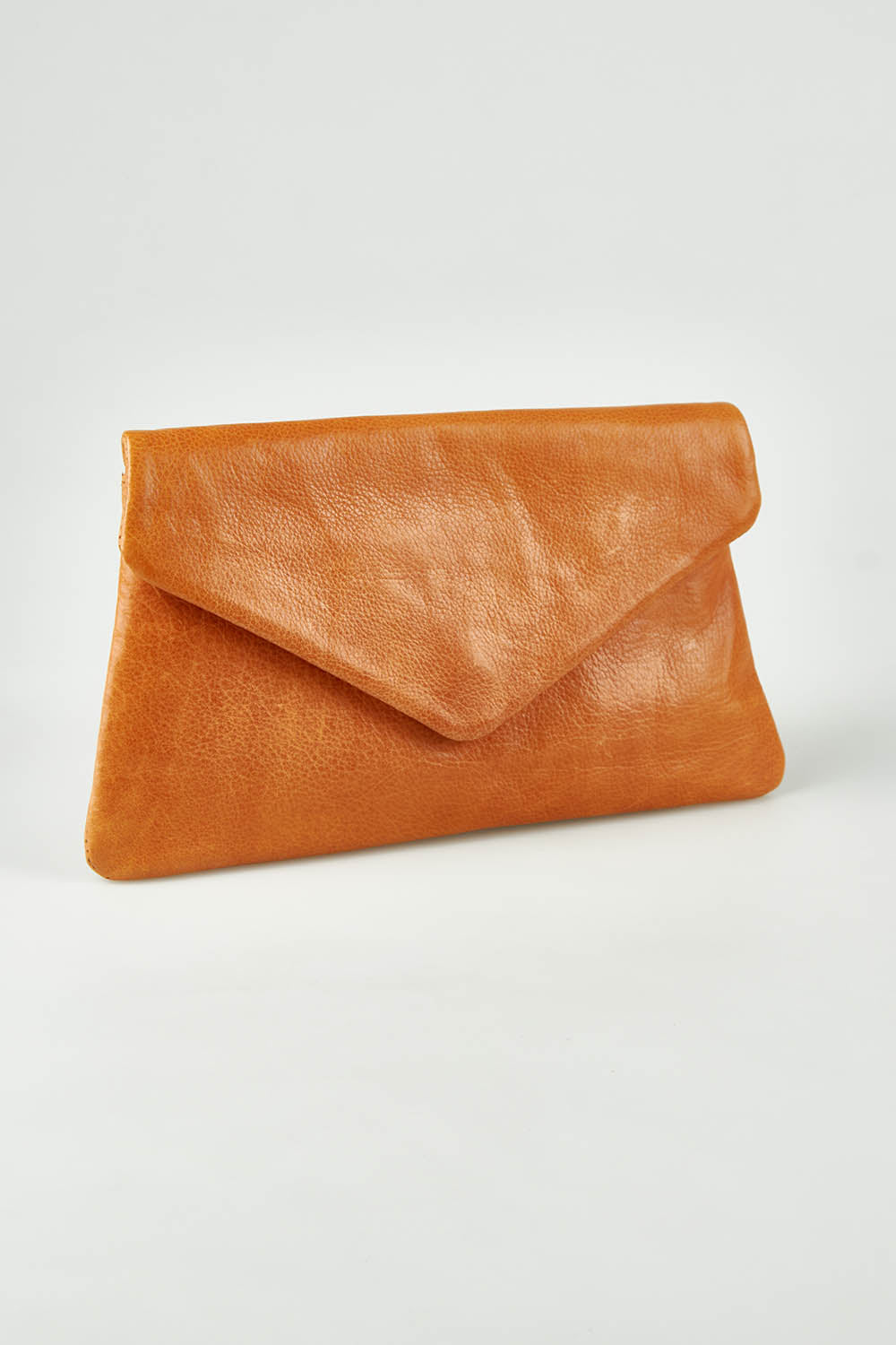 A model wearing the Riley Leather Clutch in colour Tan, from the front, showing the whole outfit