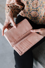 A model wearing the Rose Leather Purse in colour Duskypink (Pink), from the front, showing the whole outfit
