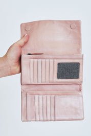 Model Steph wearing size OneSize of the Rose Leather Purse in colour Duskypink (Pink), from the front, cropped image