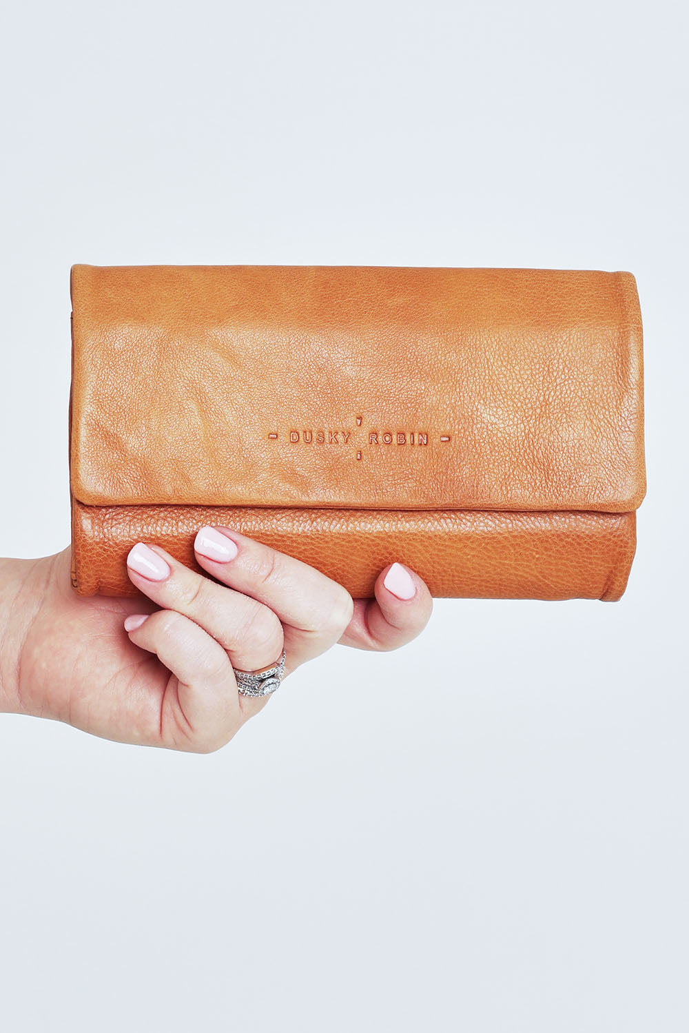 Model Steph wearing size OneSize of the Rose Leather Purse in colour Tan, from the front, cropped image