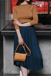 A model wearing the Sara Leather Bag in colour Tan, from the front, showing the whole outfit