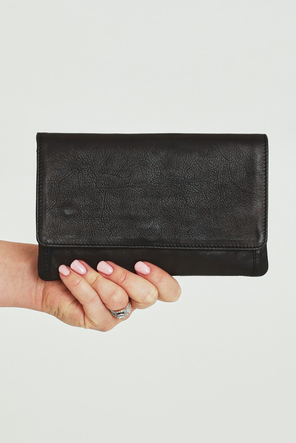 Model Steph wearing size OneSize of the Sirena Leather Purse in colour Black (Black), from the front, cropped image