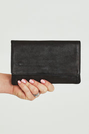 Model Steph wearing size OneSize of the Sirena Leather Purse in colour Black (Black), from the front, cropped image