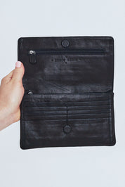 Model Steph wearing size OneSize of the Sirena Leather Purse in colour Black (Black), from the front, cropped image