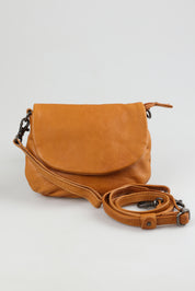 A model wearing the Zoe Leather Clutch Bag in colour Tan, from the front, showing the whole outfit