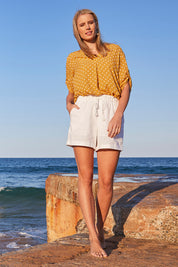 Model Maddy wearing size S of the Masai Shorts in colour Salt (White), from the front, showing the whole outfit