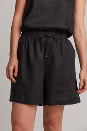 A model wearing the Studio Linen Short in colour Ebony (Black), from the front, cropped image