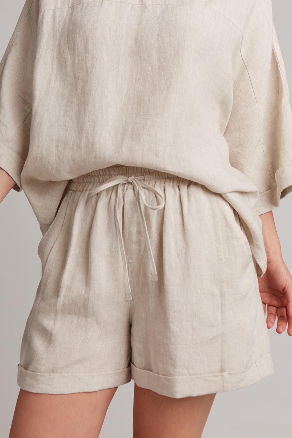 A model wearing the Studio Linen Short in colour Tusk, from the front, cropped image