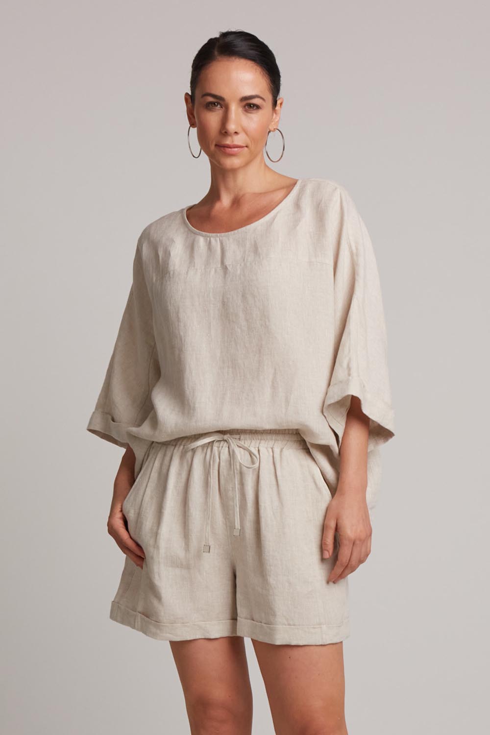 A model wearing the Studio Linen Short in colour Tusk, from the front, cropped image