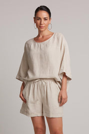 A model wearing the Studio Linen Short in colour Tusk, from the front, cropped image
