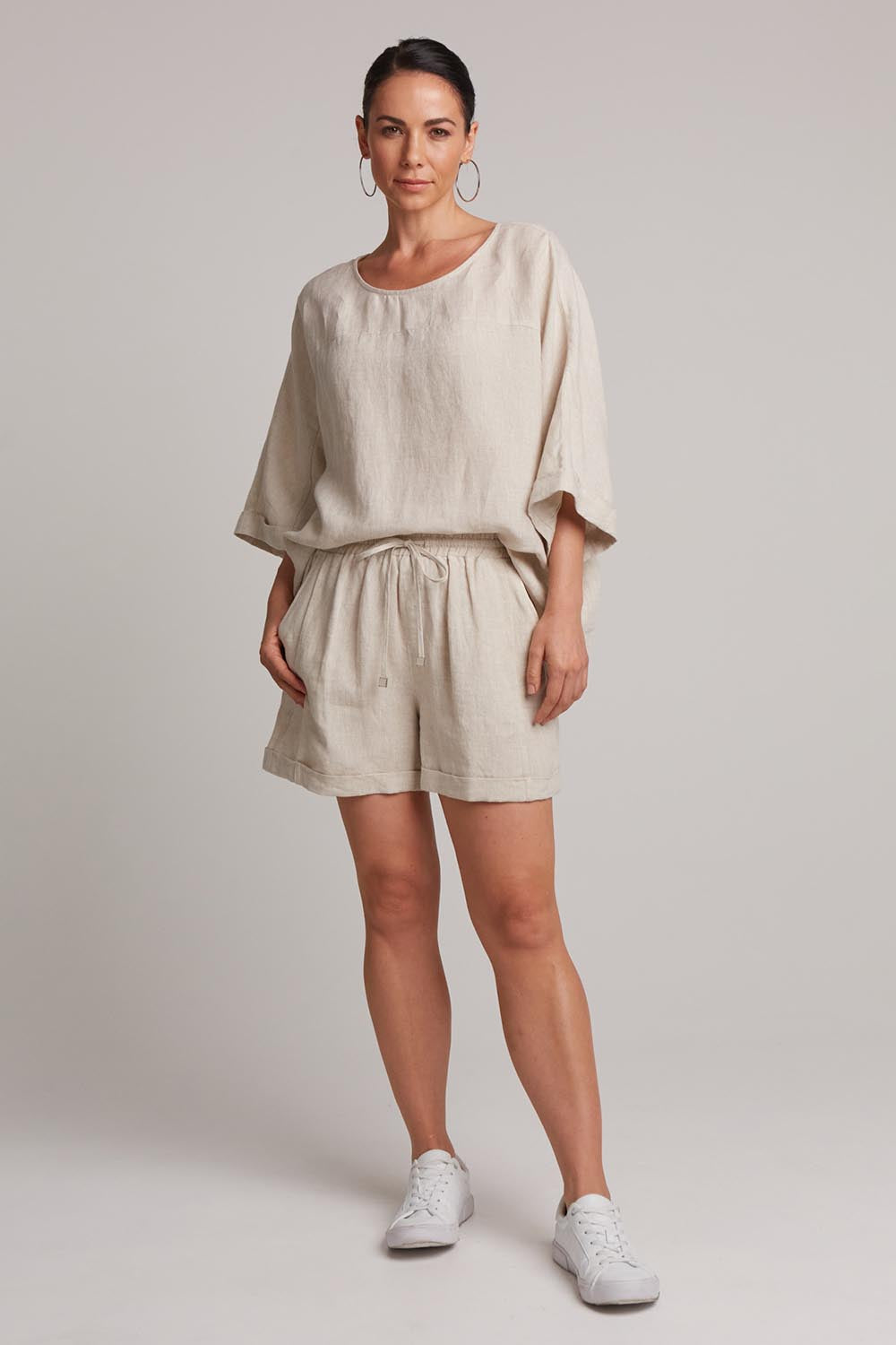 A model wearing the Studio Linen Short in colour Tusk, from the front, showing the whole outfit
